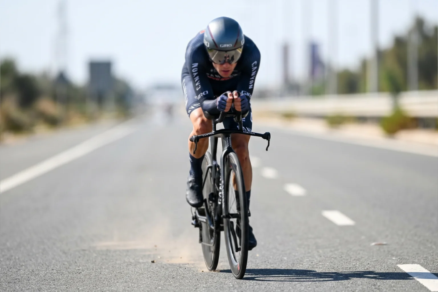 Ciclista profesional en posición aerodinámica sobre bicicleta de contrarreloj en una carretera recta